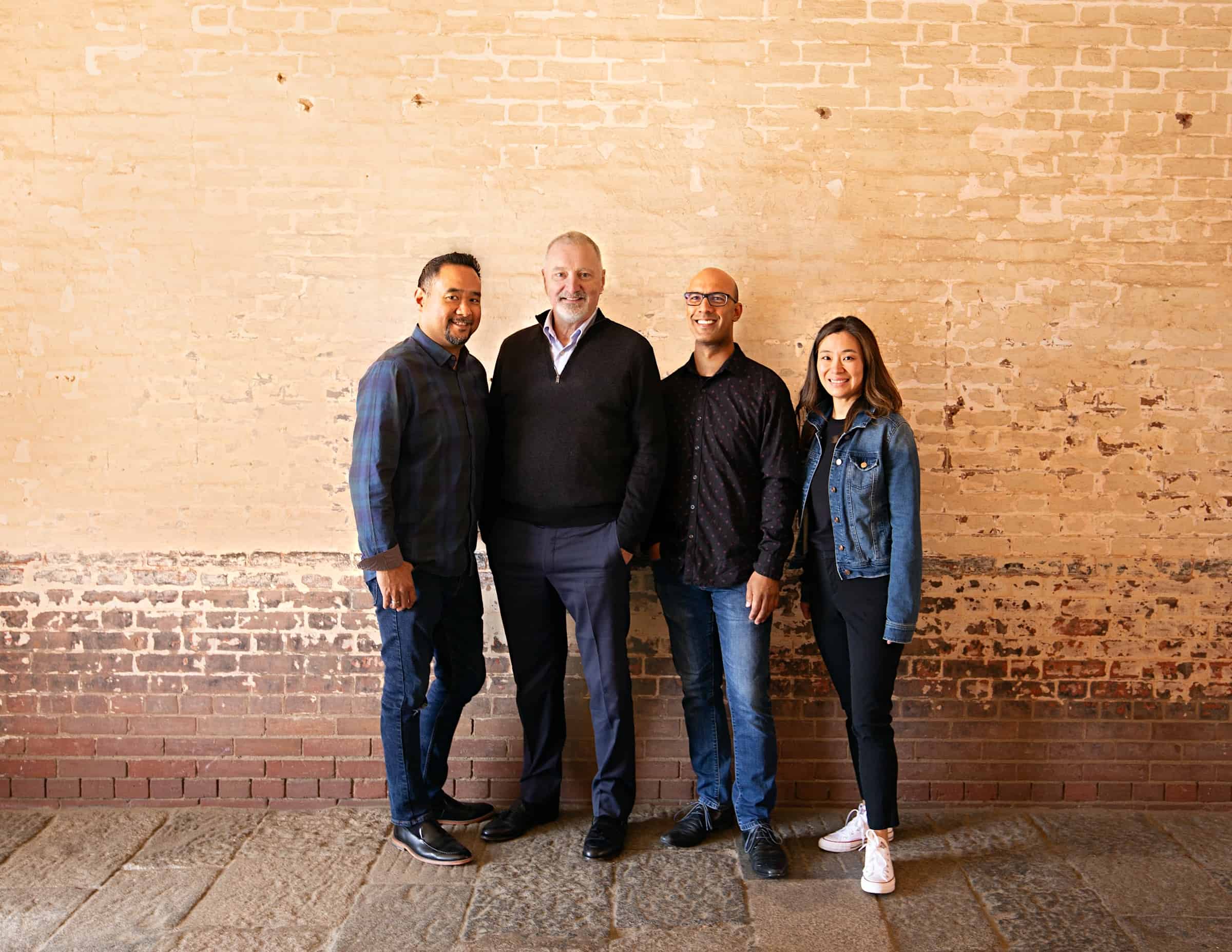 Alexander String Quartet leans against brick wall. L-R: Zakarias Grafilo, Sandy Wilson, David Samuel, Yuna Lee